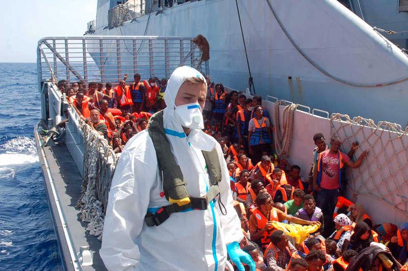Det här fotot, från augusti förra året, visar flyktingar som väntar på att få kliva ombord på kustbevakningens fartyg utanför Lampedusa.
