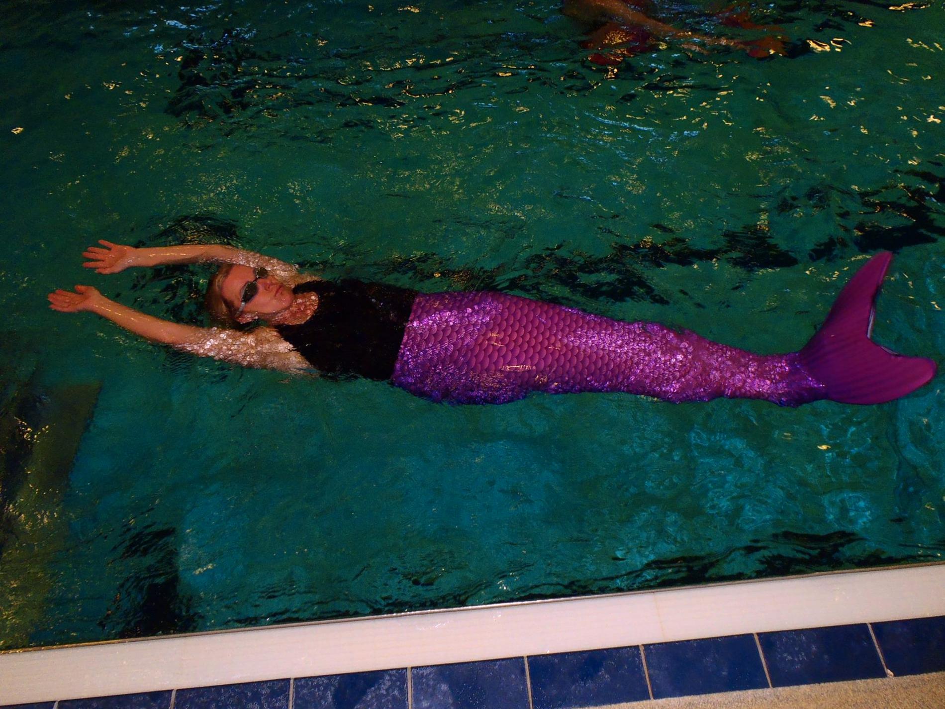 Anne Asterhäll, verksamhetsansvarig på badet, simmar runt med rosa fena.