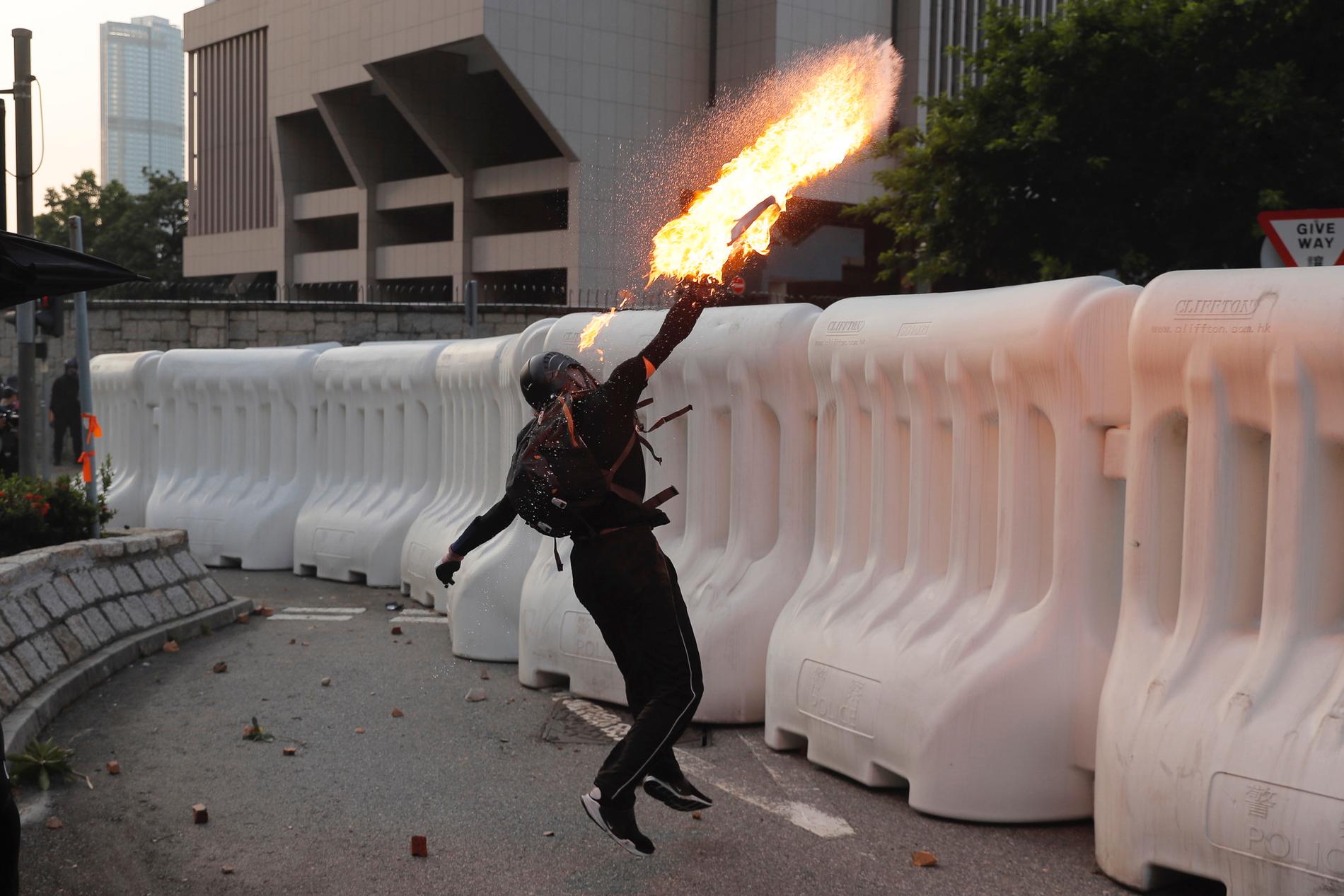 En av de protesterande Hongkongborna kastar en bensinbomb under söndagen. Delar av demonstrationen urartade i våldsamheter.