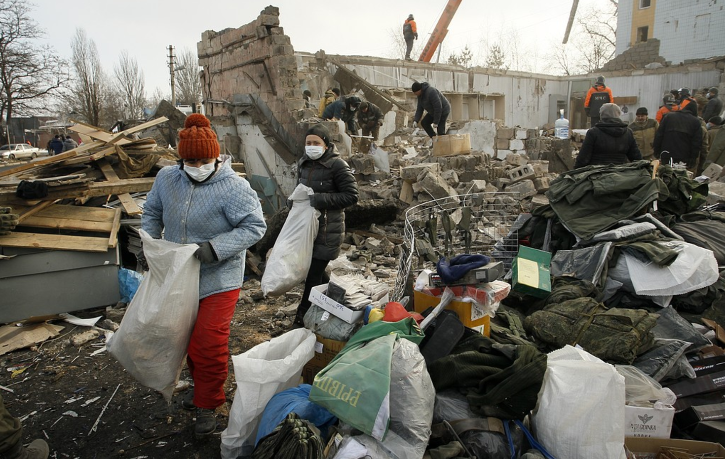 Människor samlar ihop sina tillhörigheter i ruinerna av en byggnad i Donetsk som träffades av granatbeskjutning i februari i år, då både regerings- och rebellkontrollerade områden utsattes för beskjutning.