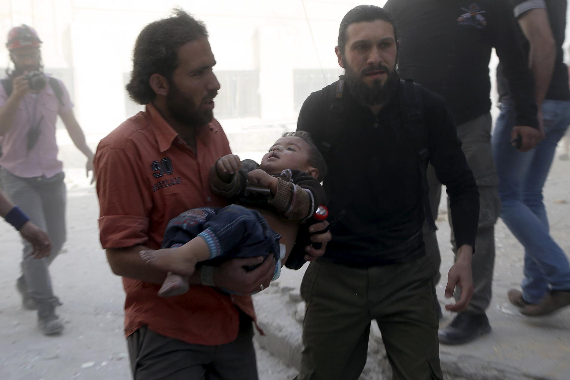 Civilförsvaret tar hand om ett skadad barn i Saif al-dawla i Aleppodistriktet. Rebeller i området hävdar att det rör sig om tunnbomber.