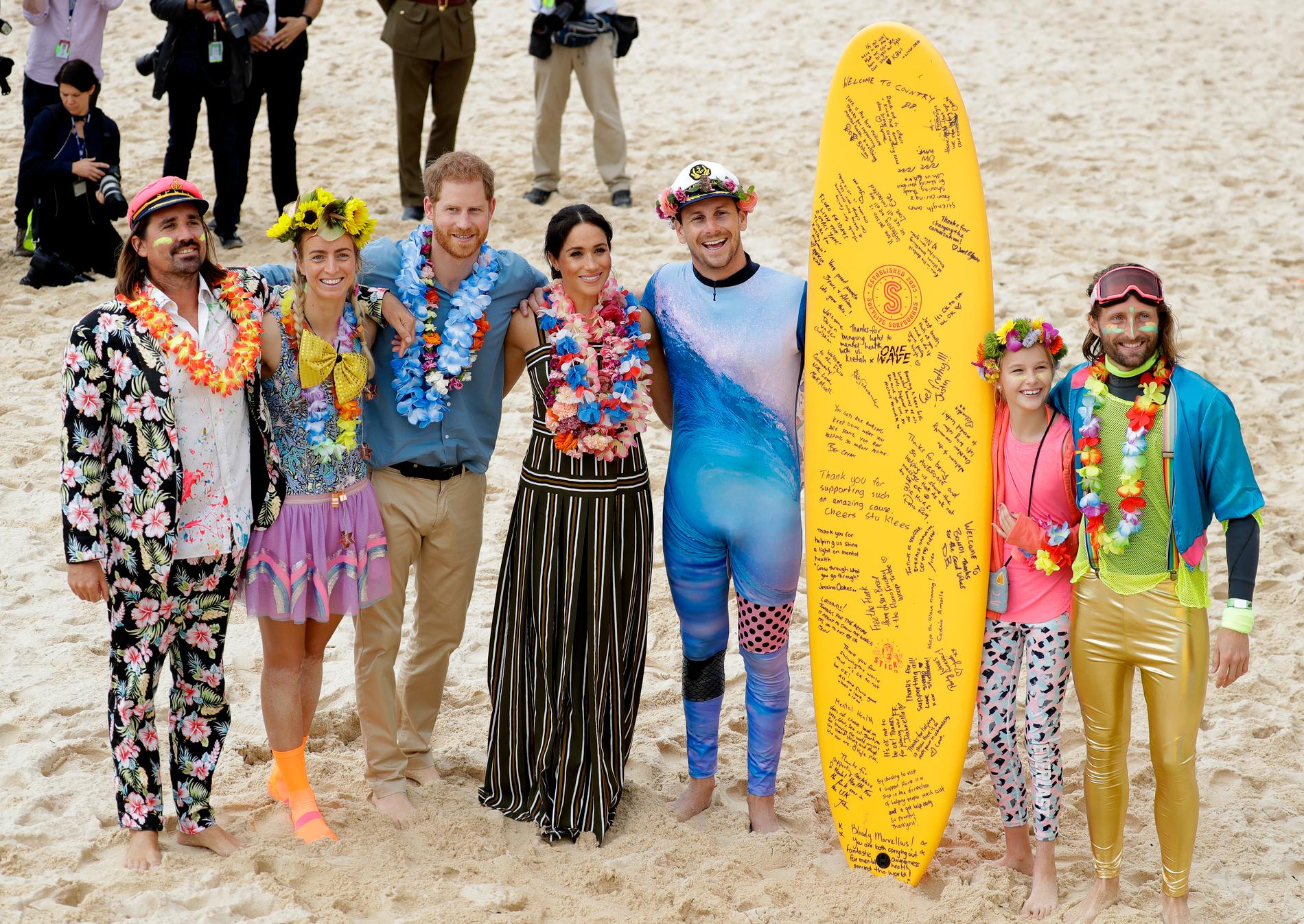 Harry och Meghan poserar med en lokal surfgrupp.
