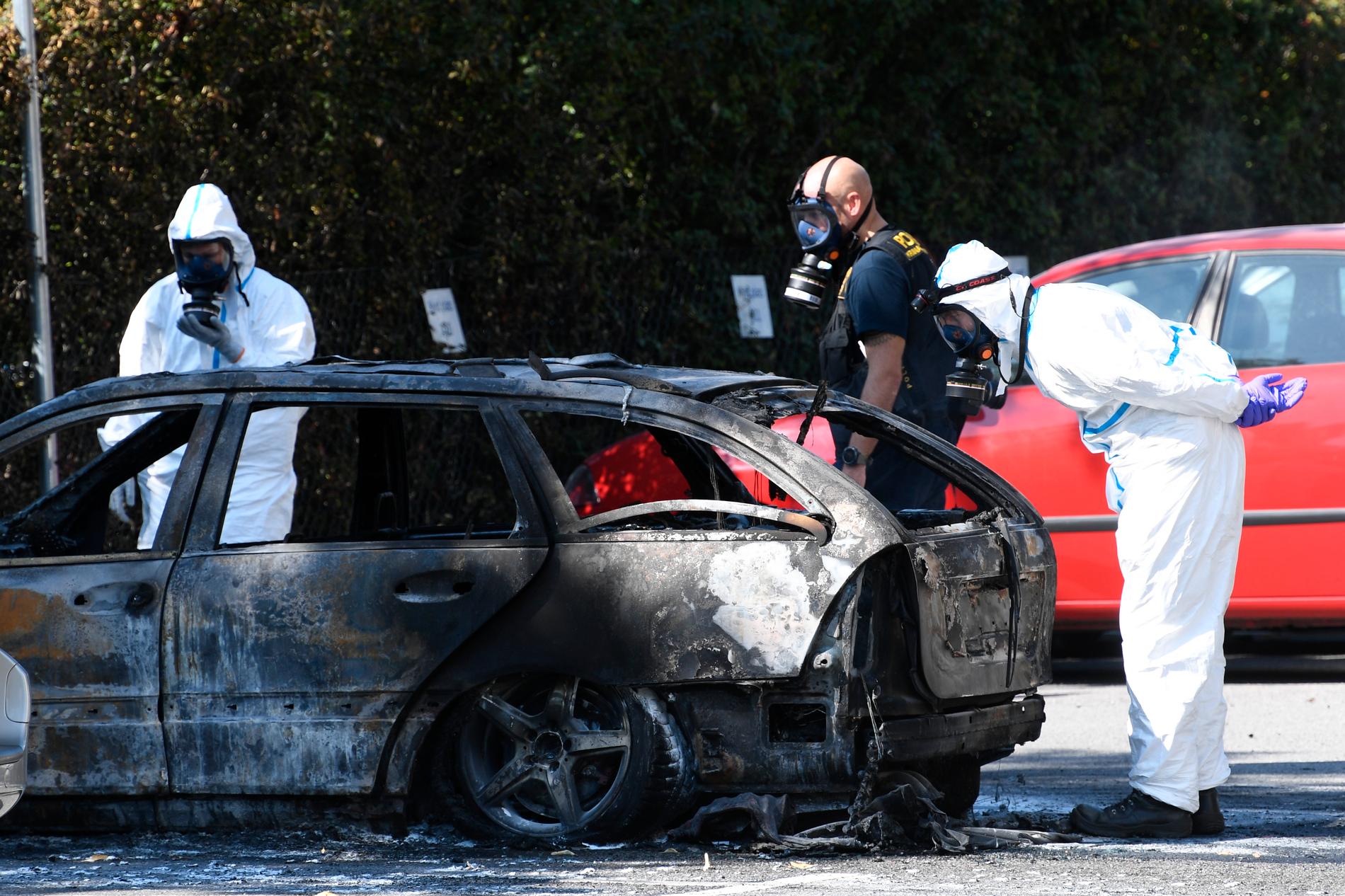 Polis och kriminaltekniker undersöker en utbrunnen bil på Stadiongatan efter skjutningen i Malmö. 