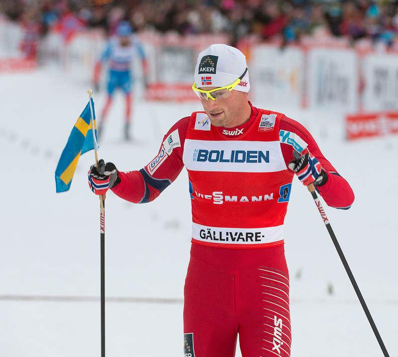 Northug korsar mållinjen med en Sverigeflagga.
