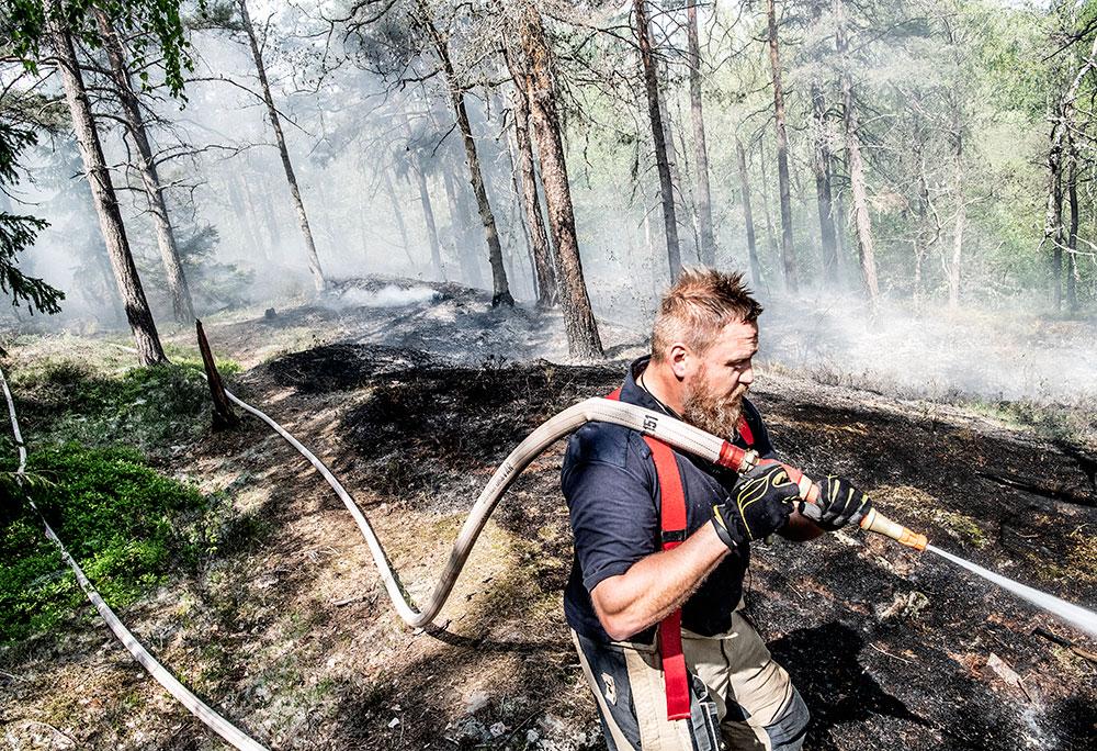 En brandman släcker en markbrand i Stortorp i maj 2019.