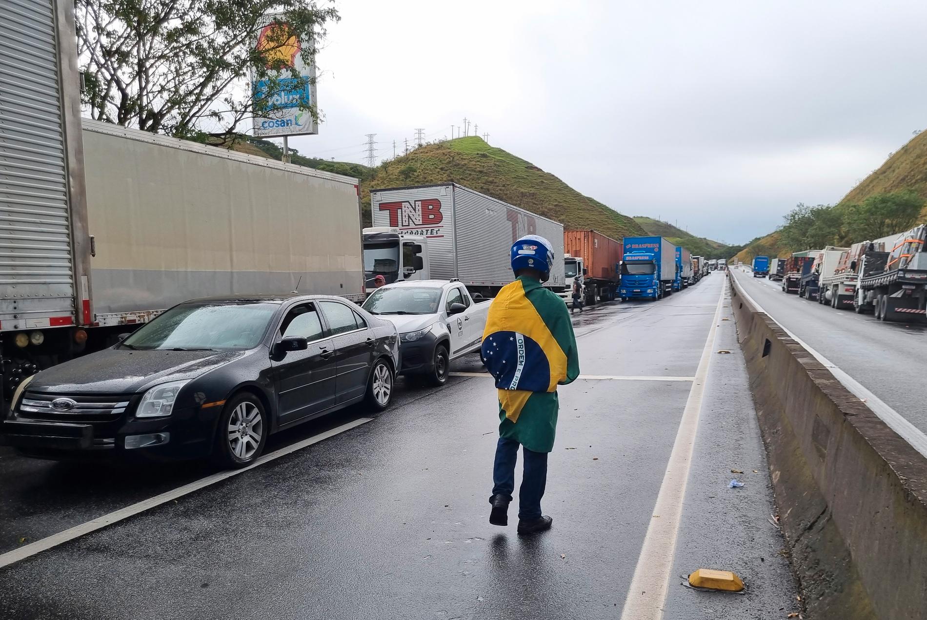  En lastbilschaufför utanför stillastående lastbilar på motorvägen mellan Rio de Janeiro och  São Paulo – parkerade i proteste mot Jair Bolsonaros valförlust.