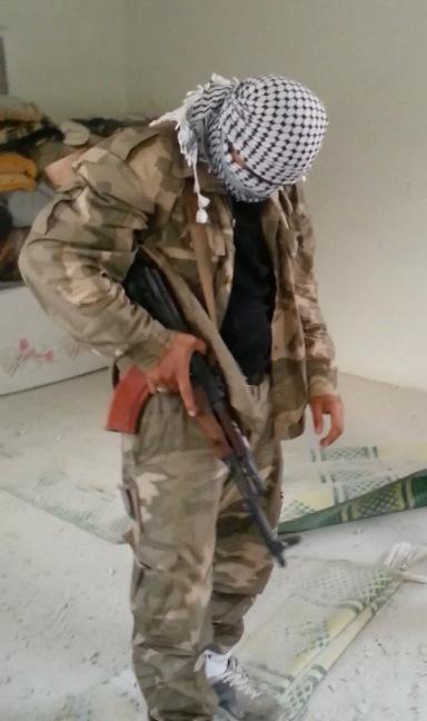 En ung svensk jihadist kontrollerar sitt vapen i ett sönderbombat hus utanför Aleppo.