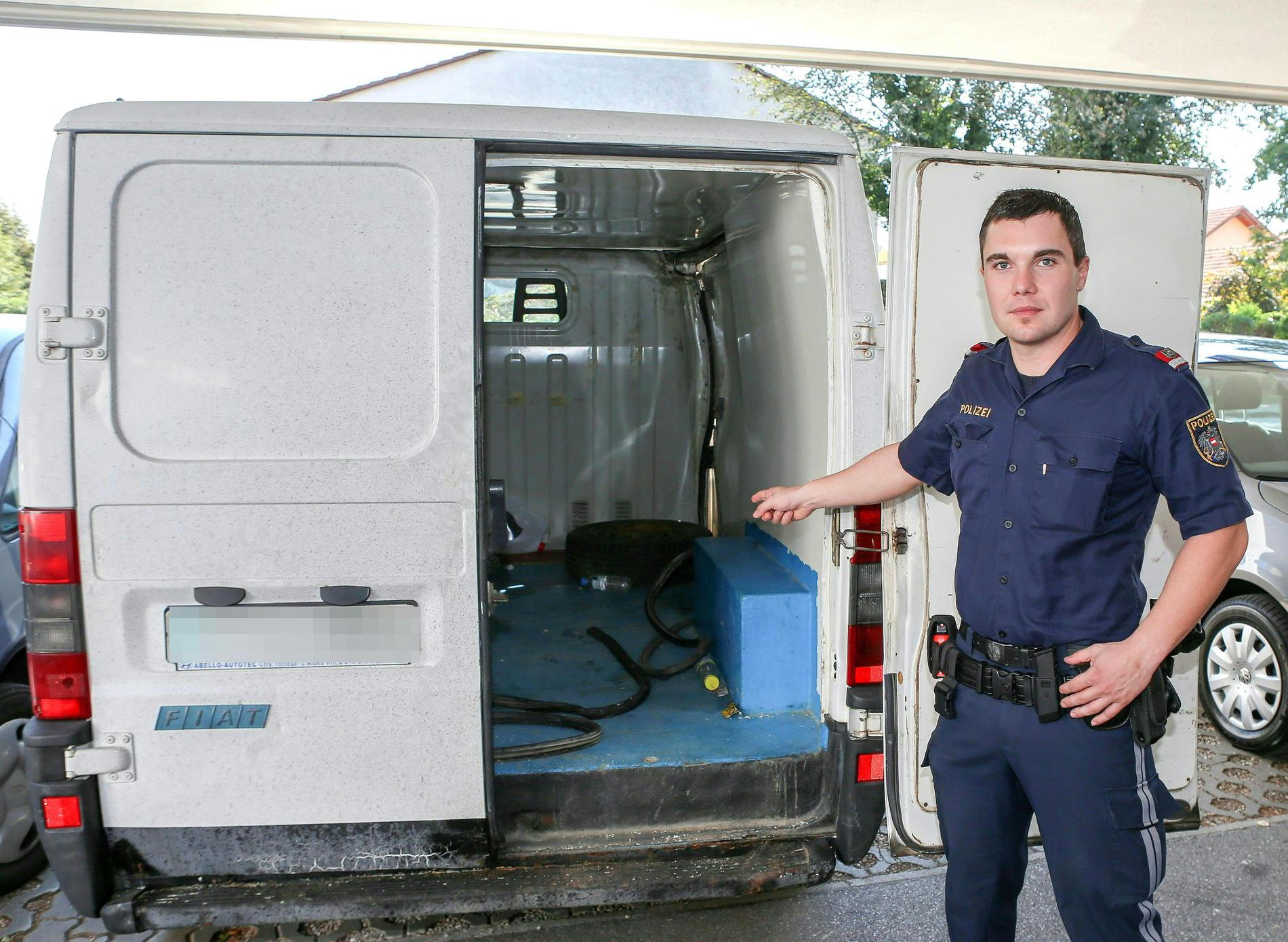 En polis i Österrike visar upp skåpbilen där 26 flyktingar hittades instängda.