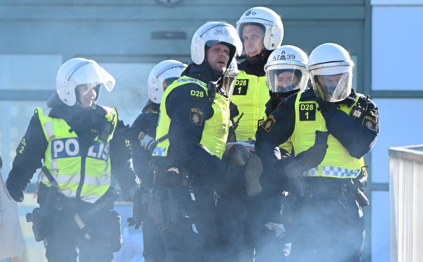 En skadad person bärs bort av polisen under kravallerna i Linköping. 