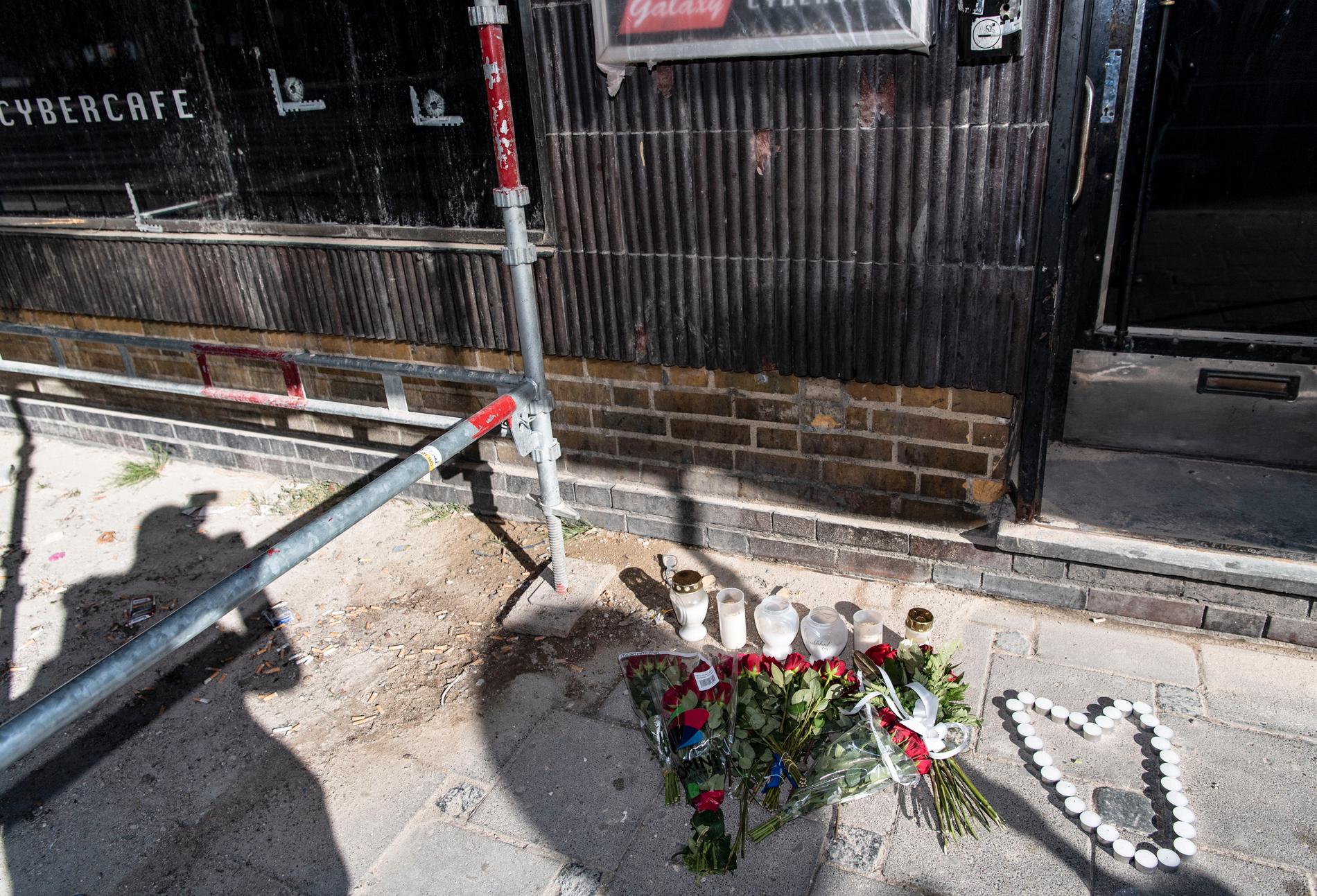 Blommor och ljus har placerats ut där tre gängkriminella män sköts ihjäl och tre andra skadades i måndags kväll.