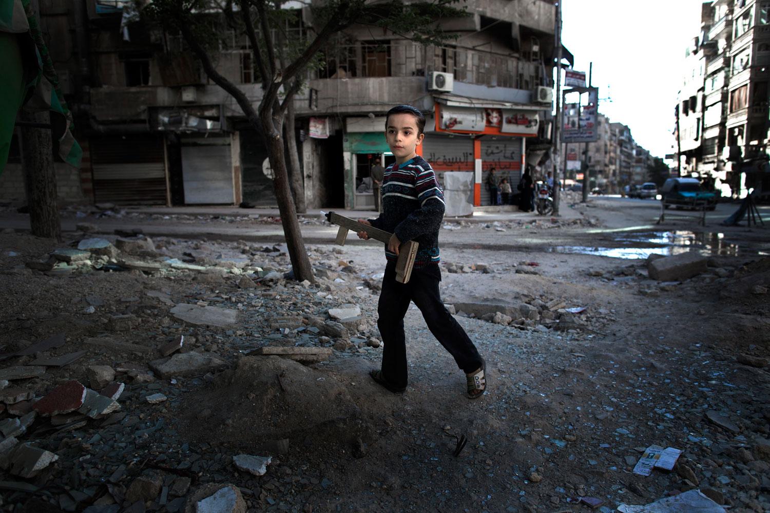 En ung pojke leker med ett hemmagjort leksaksgevär i Aleppo.