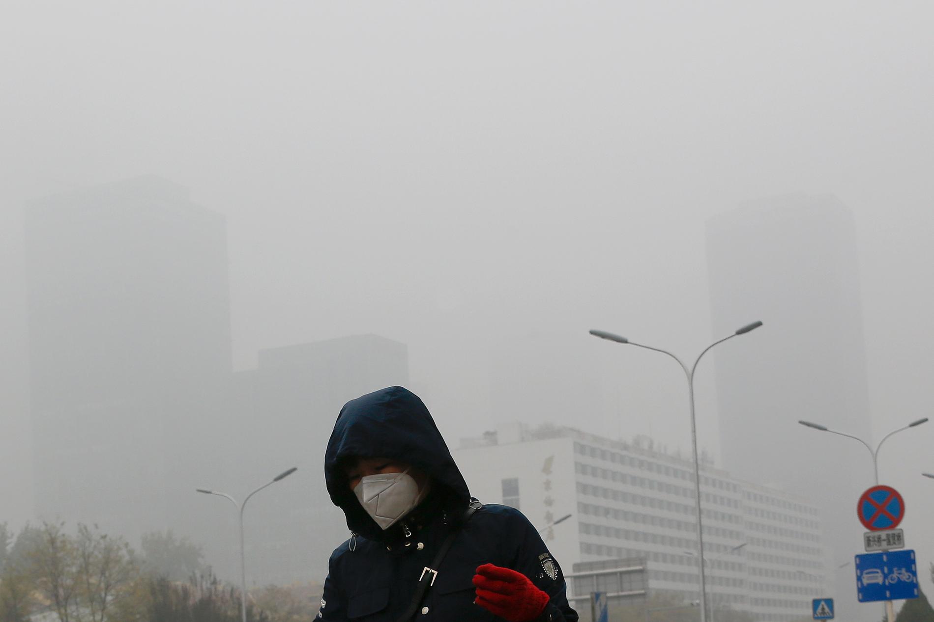 En kvinna i Beijing bär ansiktsmask för att skydda sig mot luftföroreningar i den tunga smogen. (Arkivbild från 2018.)