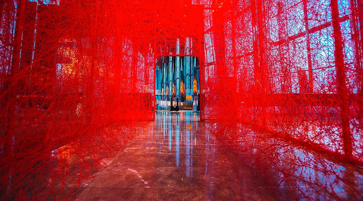 Chiharu Shiotas verk tecknar ett hus av rött garn i tre dimensioner. 