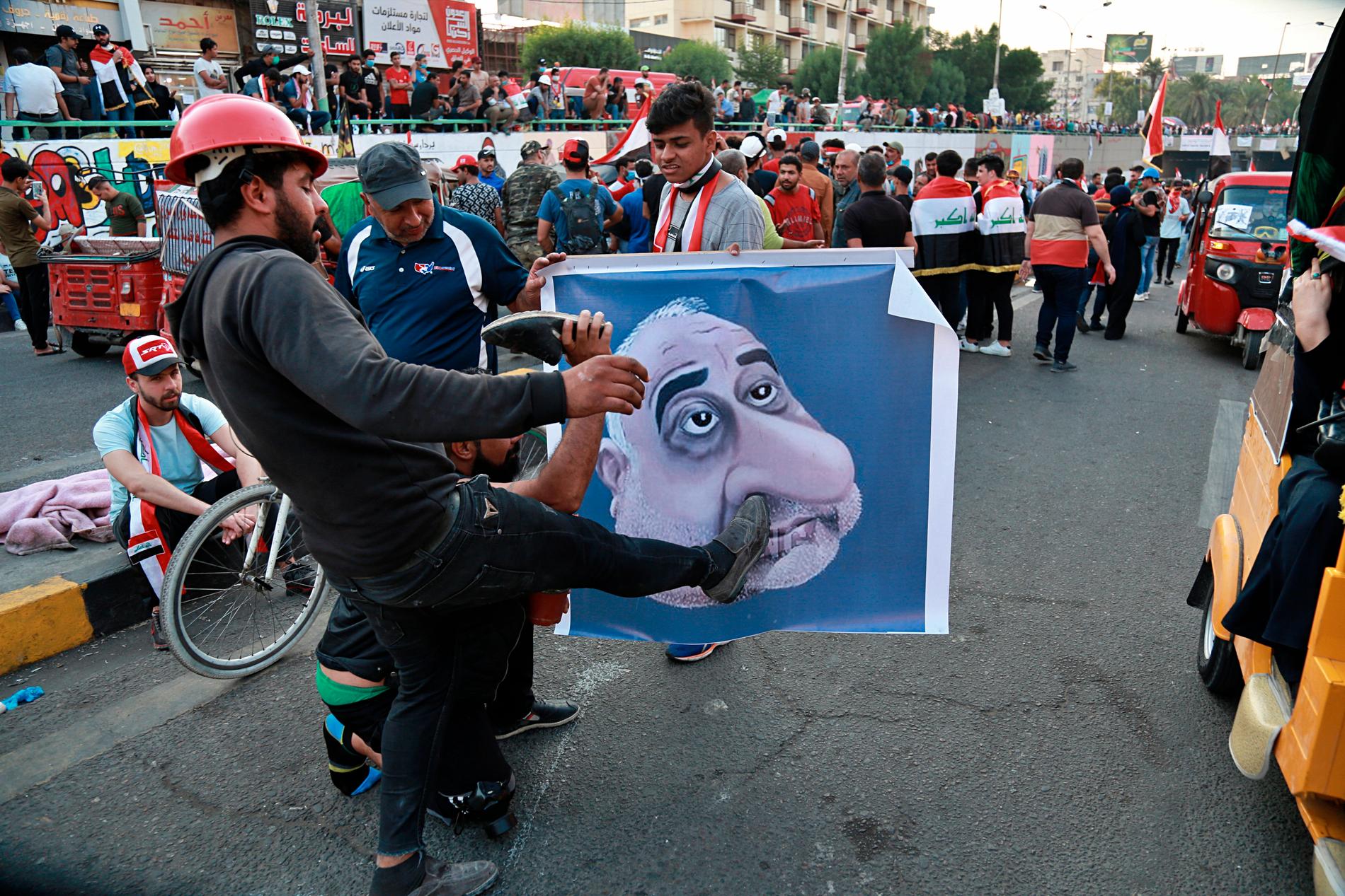 Irakiska demonstranter med ett nidporträtt av premiärminister Adil Abd al-Mahdi under förra helgens protester.