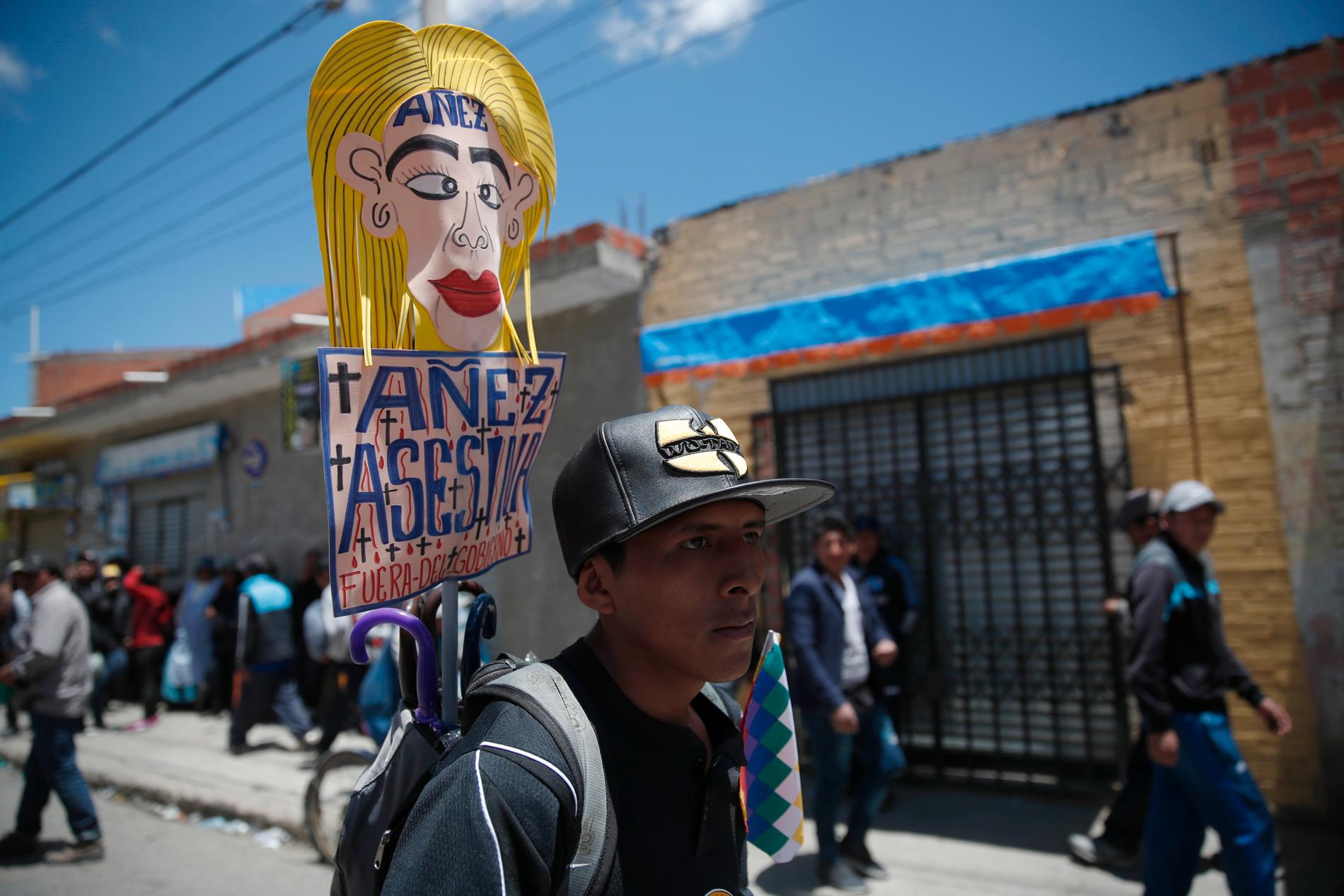 En anhängare till den tidigare presidenten Evo Morales håller ett plakat med texten "Jeanine Áñez lönnmördare, försvinn" under en demonstration i El Alto utanför huvudstaden La Paz.