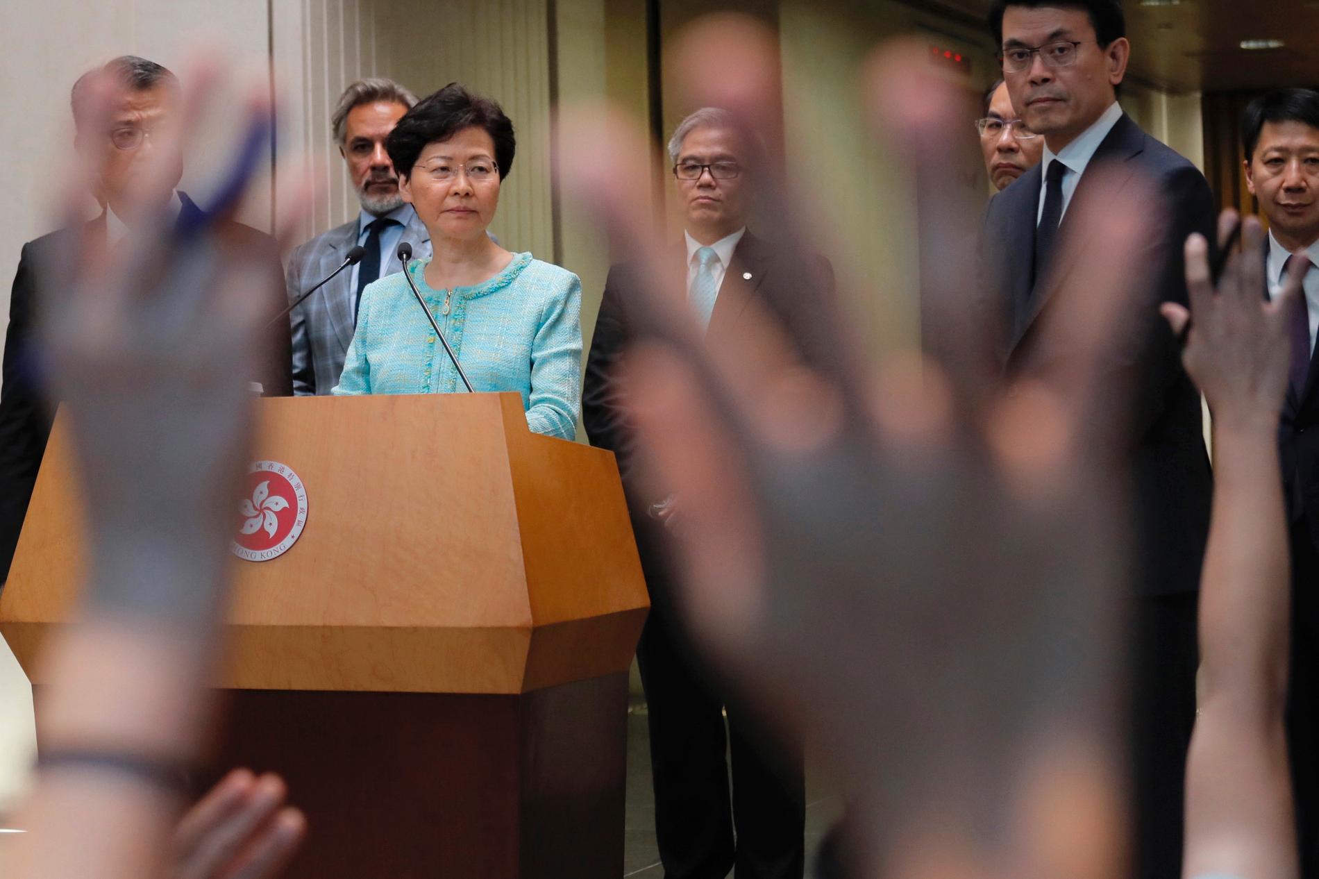 Hongkongs ledare Carrie Lam framför protesterande Hongkongbor.