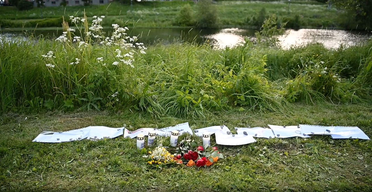 Mitt i sommargrönskan råder plötsligt sorg i det värmländska samhället. Vid älven i centrala Hagfors har man lämnat blommor och ljus för att hedra den döde pojken.