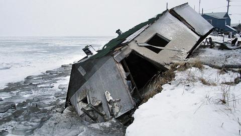 HAVET ÄTER UPP JORDEN Ett av husen i Shishmaref, Alaska, underminerades av stormvågorna och föll ner från strandkanten under en storm 2005. Snart måste hela byn flytta – innan samma sak händer även de andra husen. Allt som allt kommer flytten att kosta över en miljard svenska kronor för eskimåbefolkningen. Pengar de inte har.