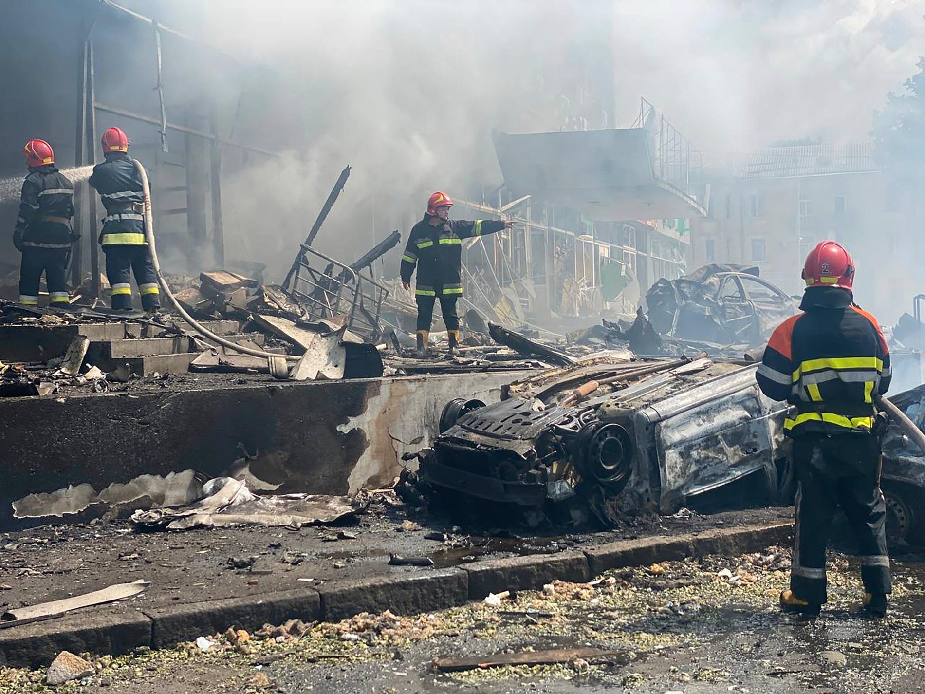 Räddningsarbetare jobbar för att släcka branden i en byggnad som förstörts i attackerna. 