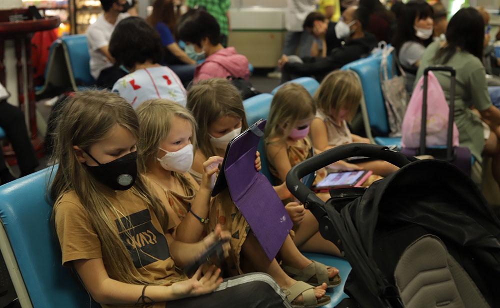 Barnen i väntan på ett flyg hem. De bar munskydd som de flesta andra passagerarna. 