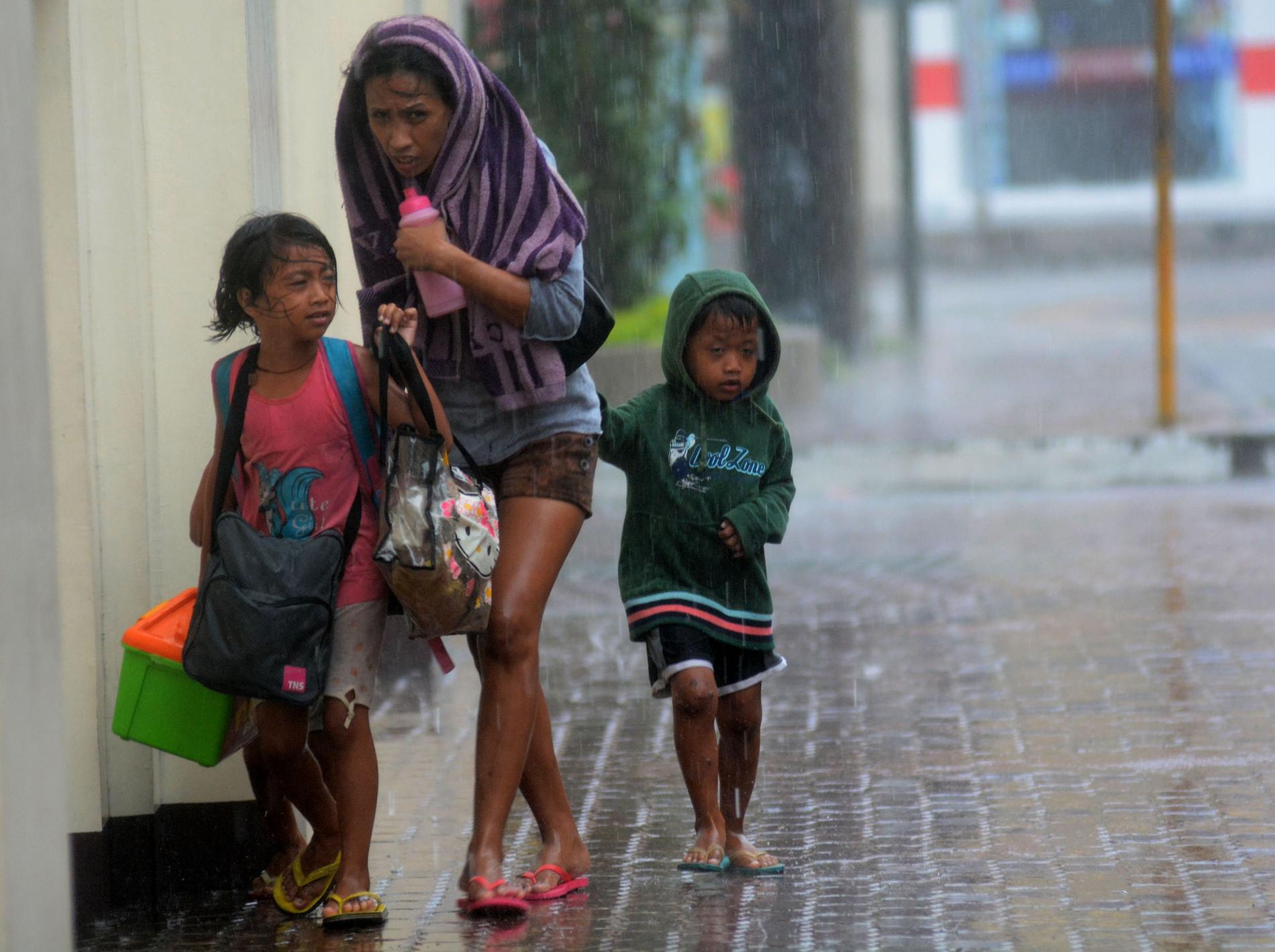 En mamma och hennes två barn flyr till ett evakueringscentrum i Cebu City.