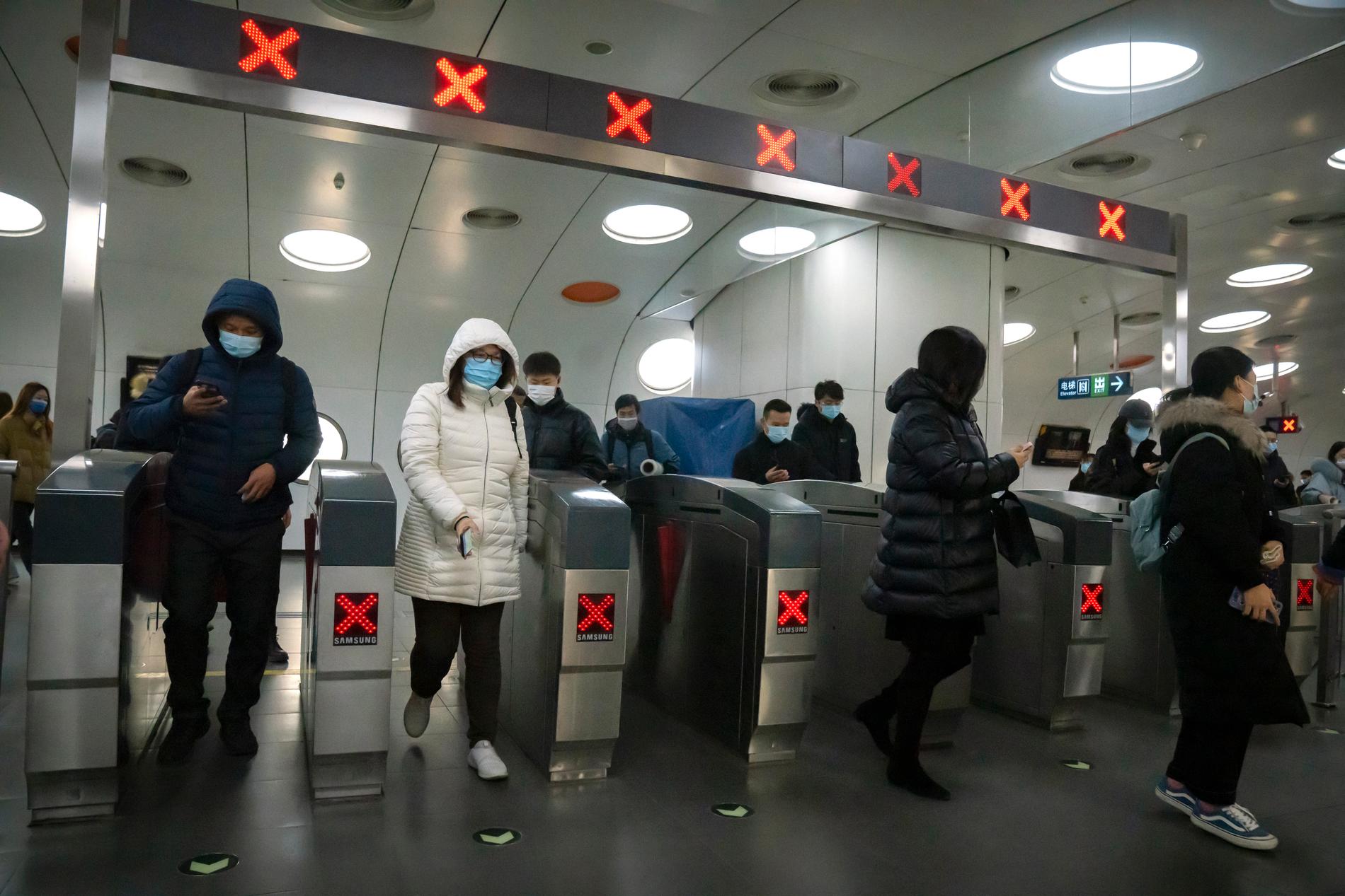 Människor med ansiktsmasker i tunnelbanan i Peking i Kina.