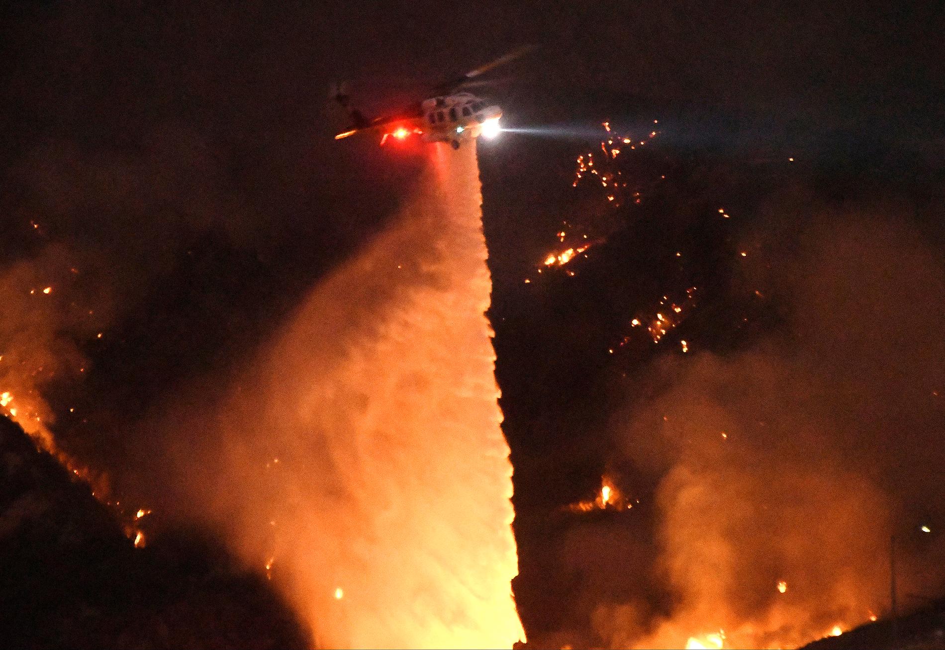 En helikopter släpper vatten på branden i ett skogsområde nära Los Angeles.
