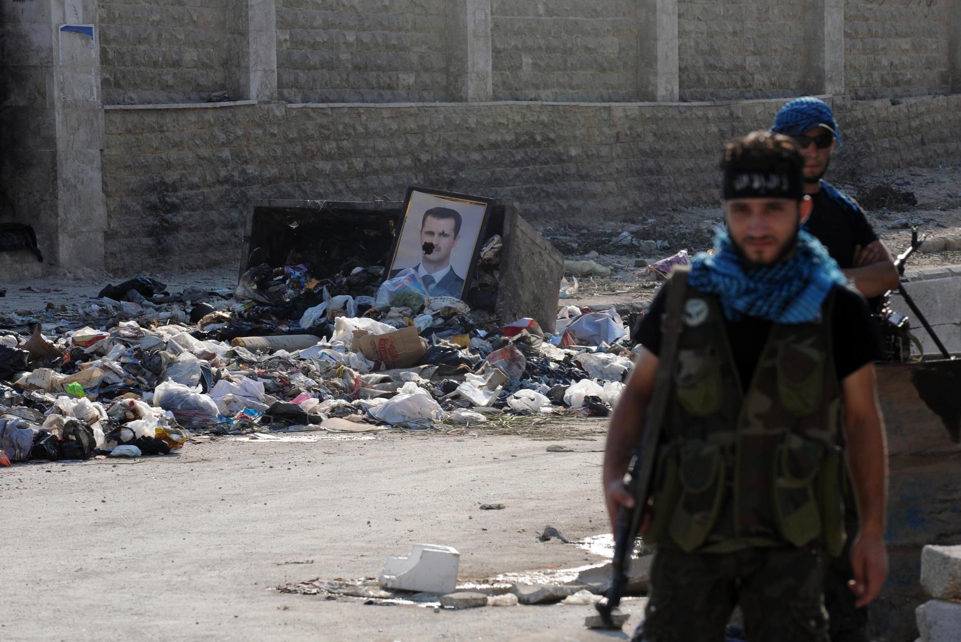 Rebellsoldater framför ett porträtt av Bashar al-Assad.