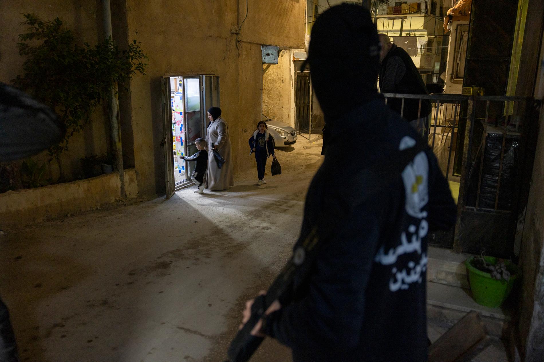 En mamma med barn handlar i en butik. Gatan vaktas av Palestinska Islamiska Jihad.