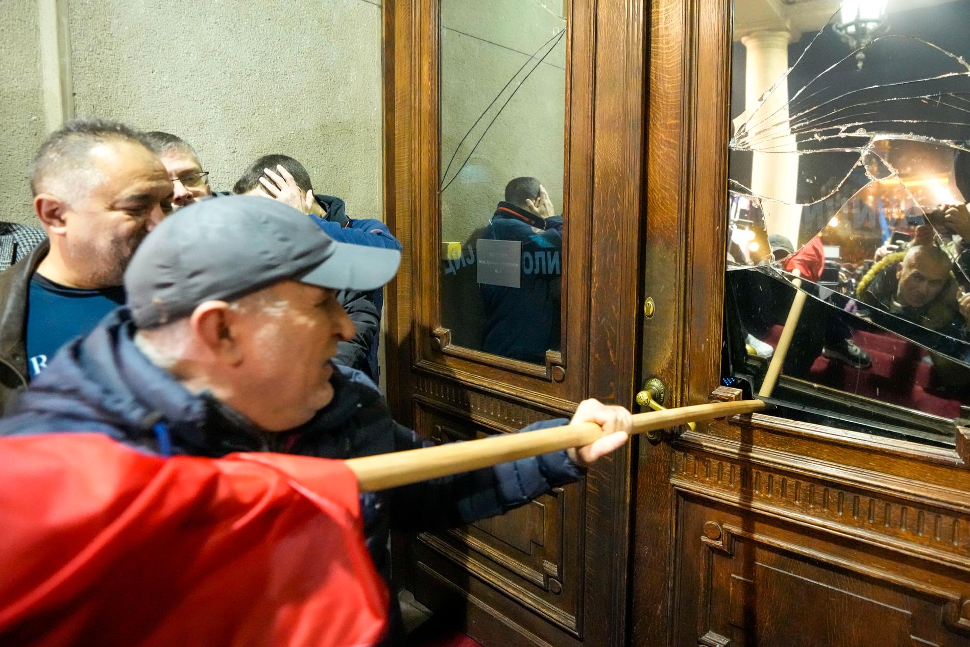 Upprörda demonstranter försöker ta sig in i stadshuset i Belgrad. 