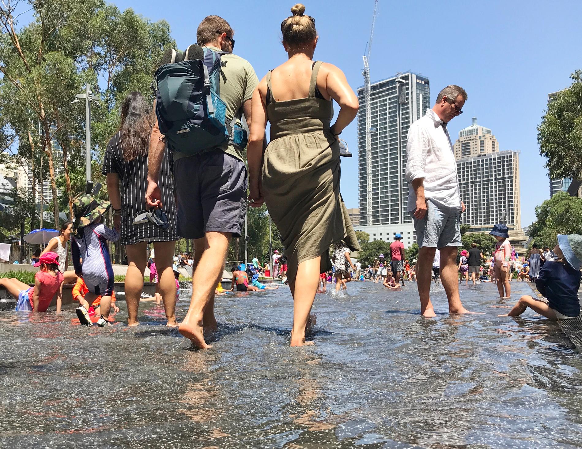 Människor söker svalka i en plaskdamm i Tumbalong Park i Darling Harbour i centrala Sydney en varm januaridag.