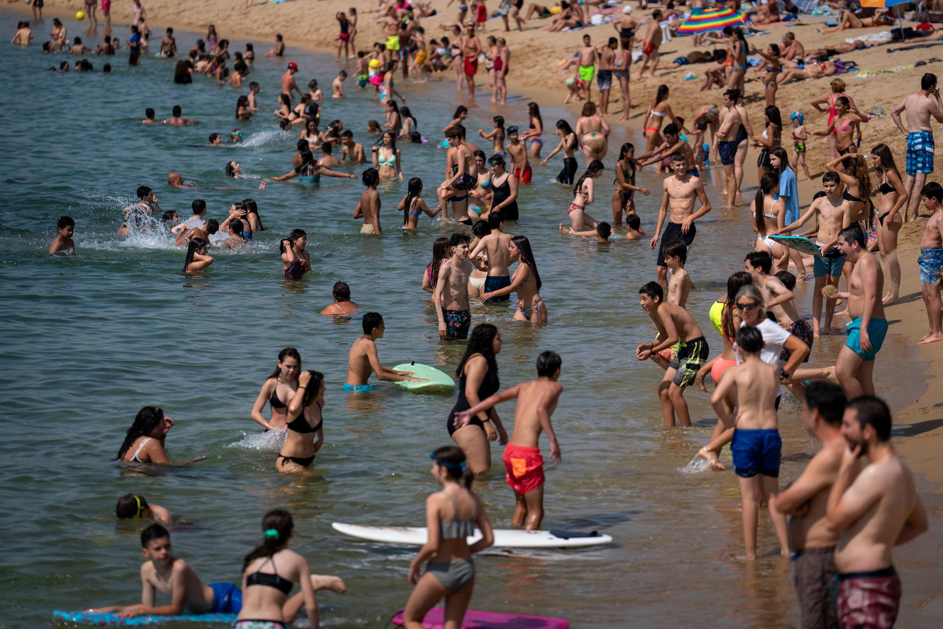 Fullt av människor på en strand i Barcelona. 