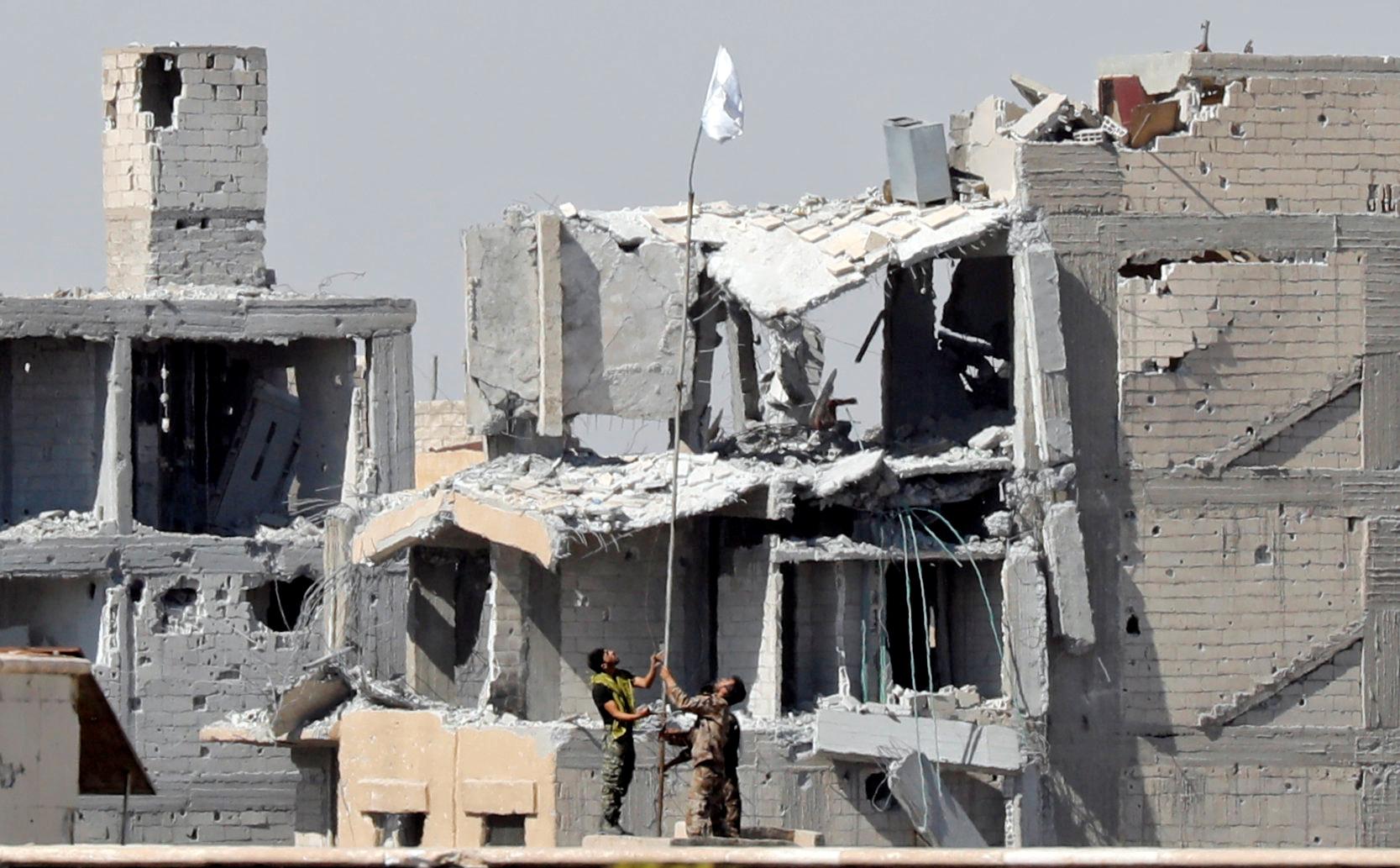 SDF-soldater hissar en vit flagga från ett sjukhus som tidigare hölls av IS.