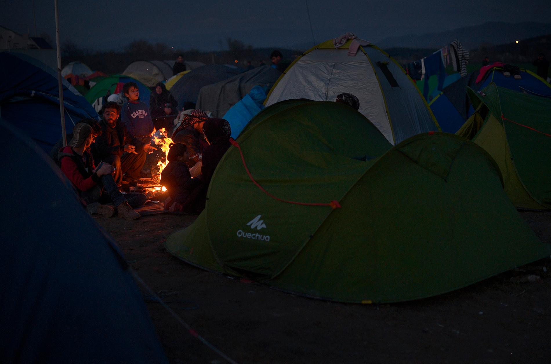 Det är dags att gå och lägga sig i flyktinglägret vid gränsen mellan Grekland och Makedonien. Efter att solen försvunnit bakom bergen tar det bara en halv timme till det att det är helt mörkt i lägret. Man släpar sina nyinköpta tält och sätter upp dem på någon av åkrarna vid gränsen. Man eldar kvistar, grenar och skräp för att hålla värmen.