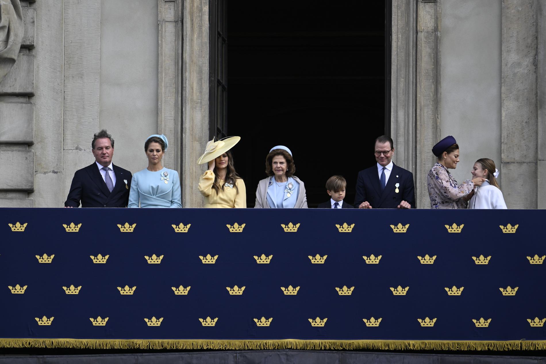 Chris O'Neill, prinsessan Madeleine, prinsessan Sofia drottning, Silvia, prins Oscar, prins Daniel, kronprinsessan Victoria och prinsessan Estelle tittar på från balkonen under högvaktsavlösningen.