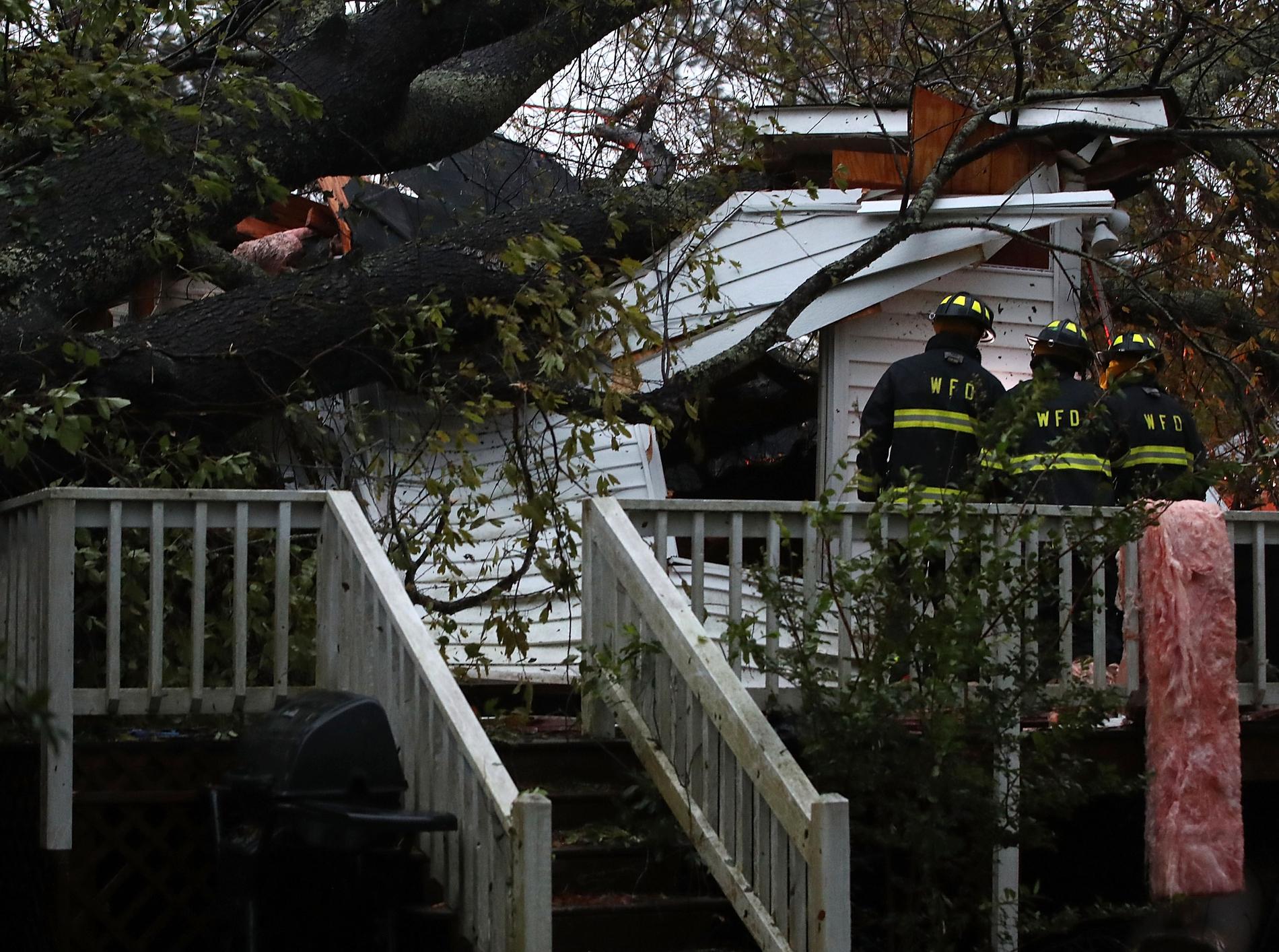 Räddningspersonal utanför ett hem. Ett träd har fallit på huset och tre personer blev instängda. 