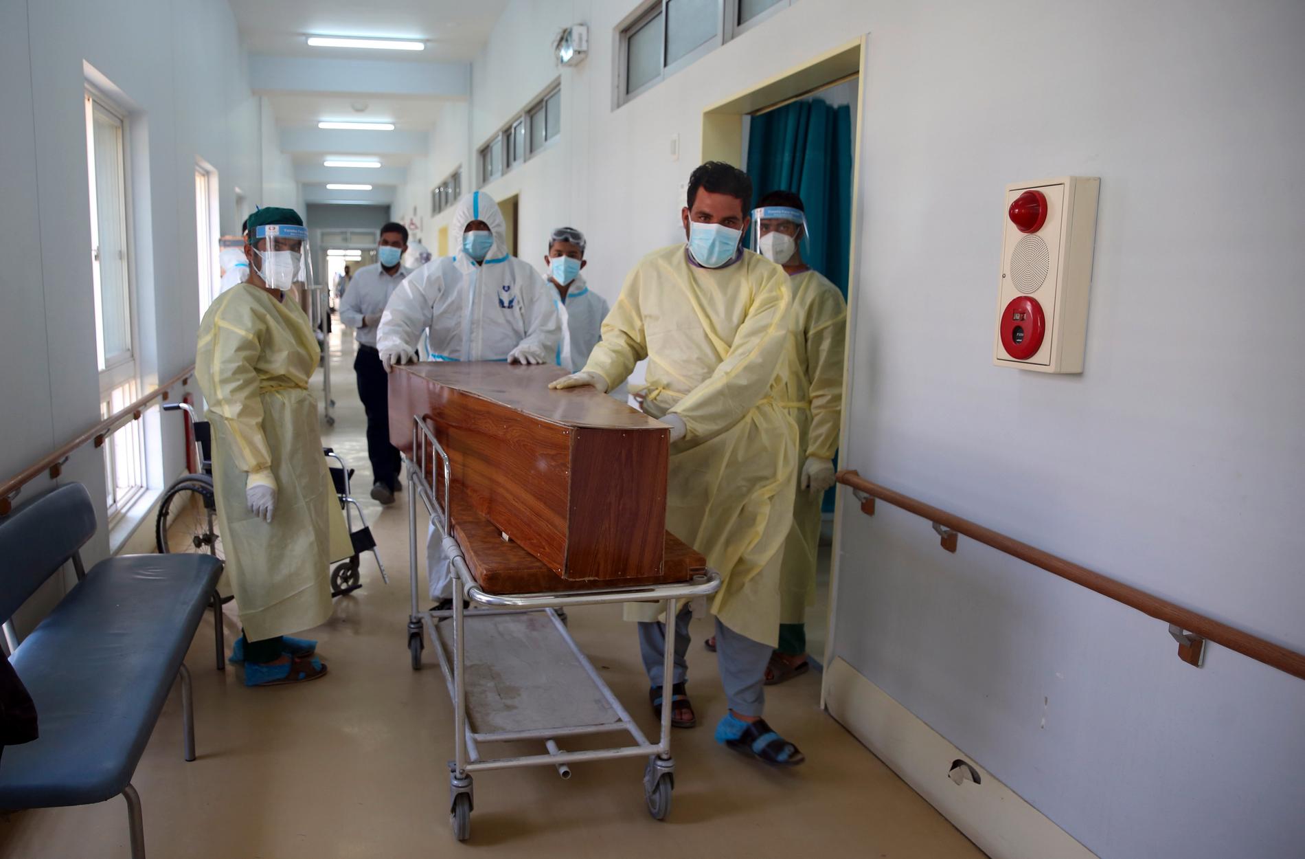 Afghanska vårdarbetare för en man som avlidit i covid-19 längs en sjukhuskorridor i Kabul. Arkivbild.