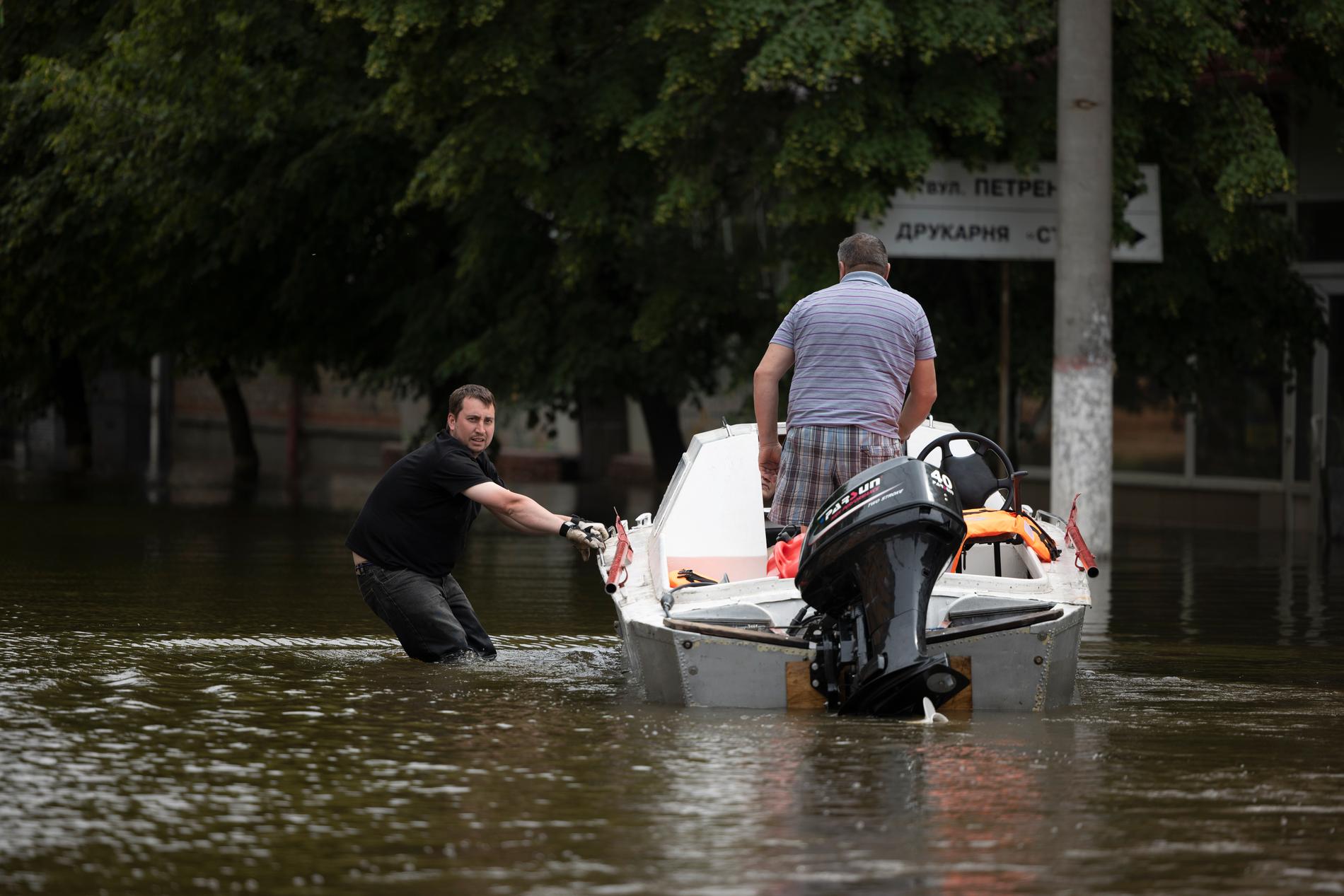 Hjälparbetare åker med båt i staden för att evakuera både människor och djur.