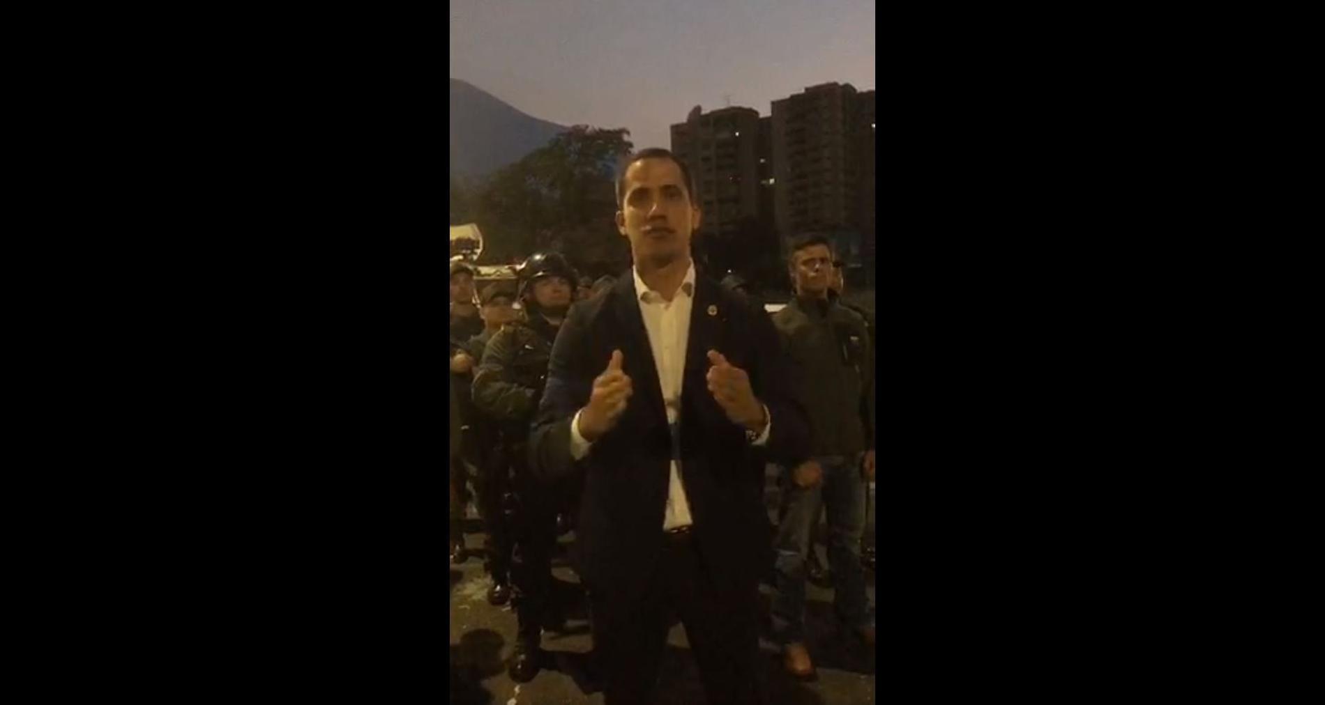 Skärmbild från videon där Juan Guaidó talar och flera militärer står bakom honom.