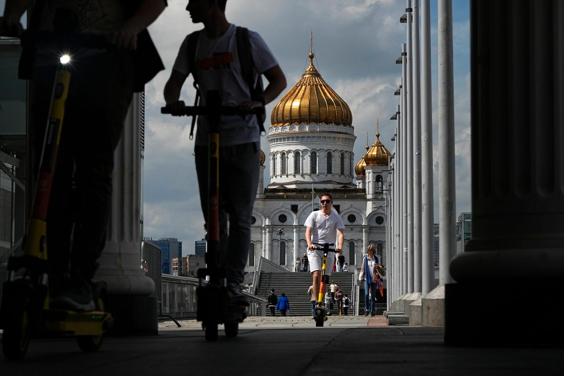 Människor på elsparkcykel vid katedral i Moskva. 