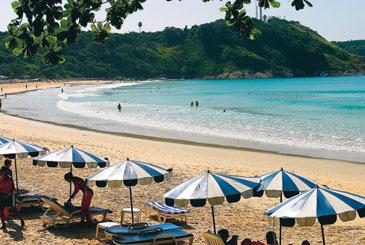 På den fina stranden Nai Harn på Phukets sydkust står solstolarna på rad.