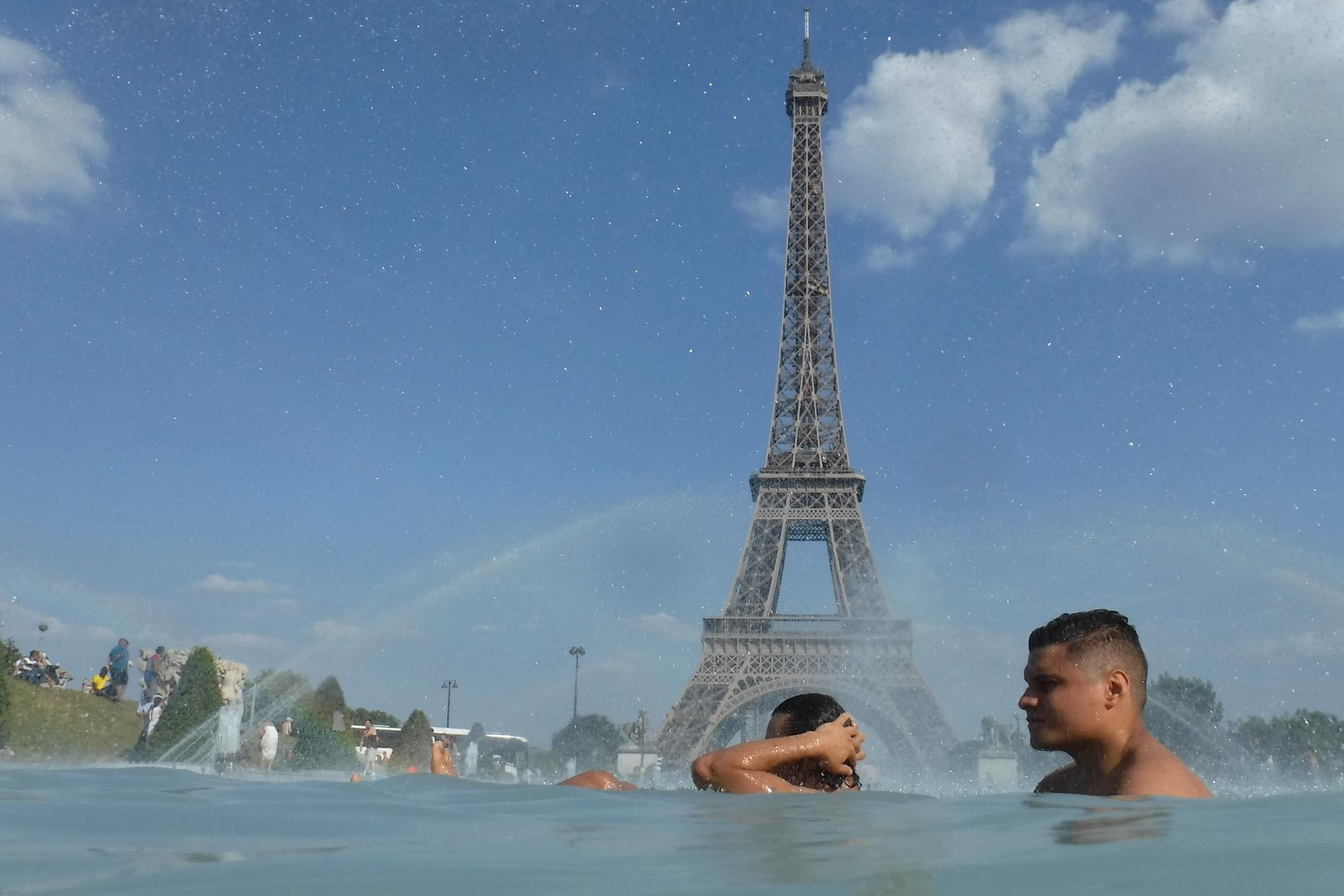 Människor svalkar sig i fontänen på torget Trocadero i Paris på tisdagen.