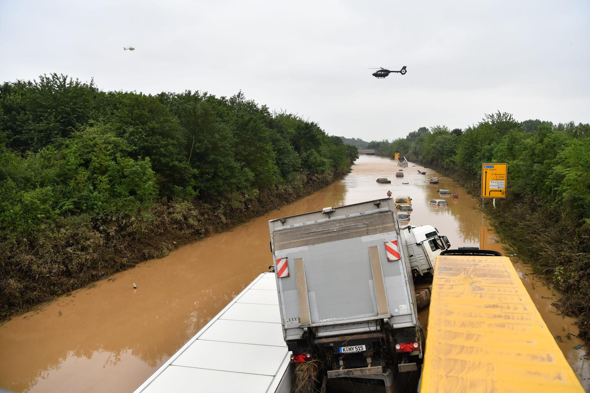 Fastkilade lastbilar på den helt översvämmade vägen. Bilar ligger 12 meter vattenytan.