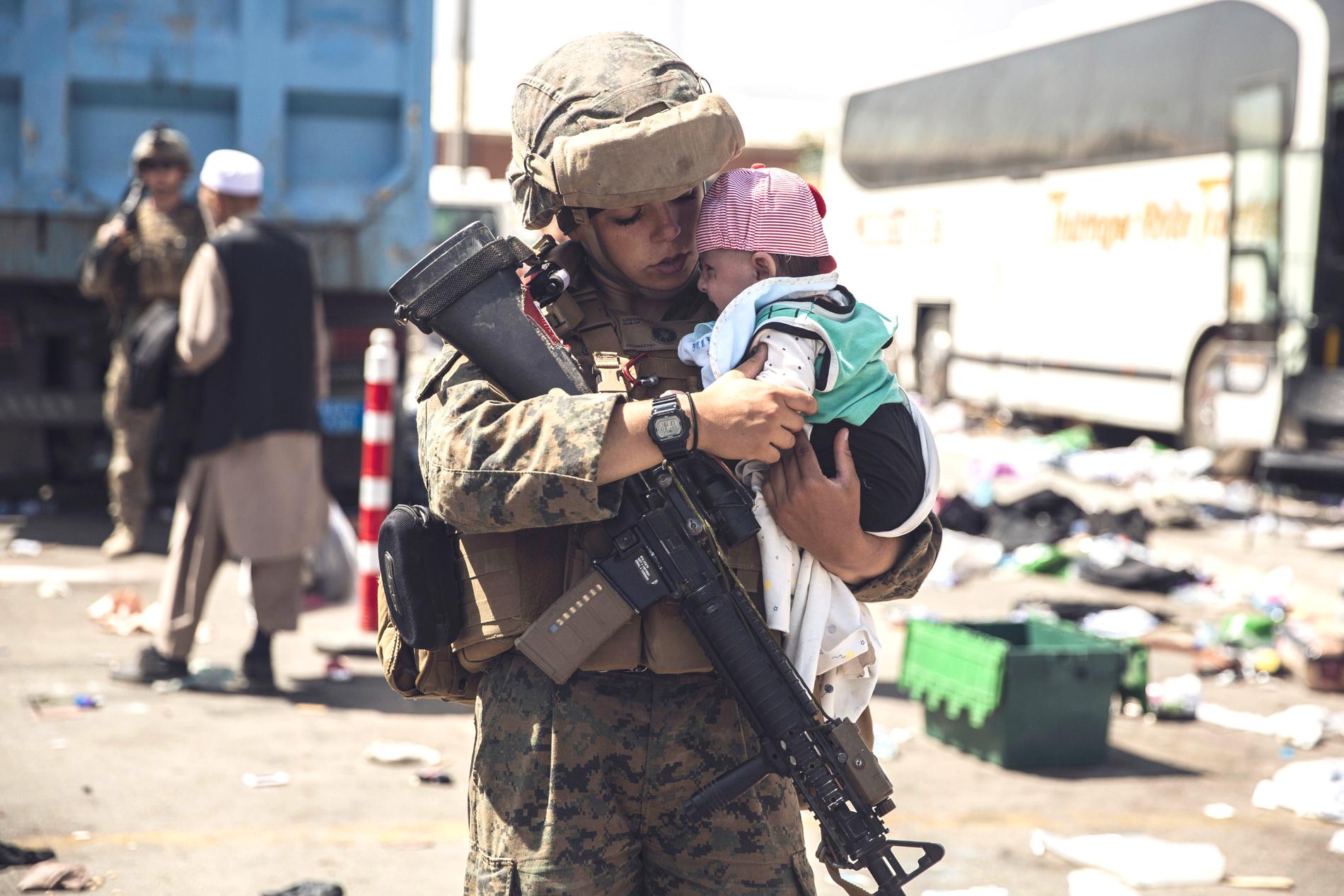En amerikansk soldat tar han om ett barn på flygplatsen i Kabul. 