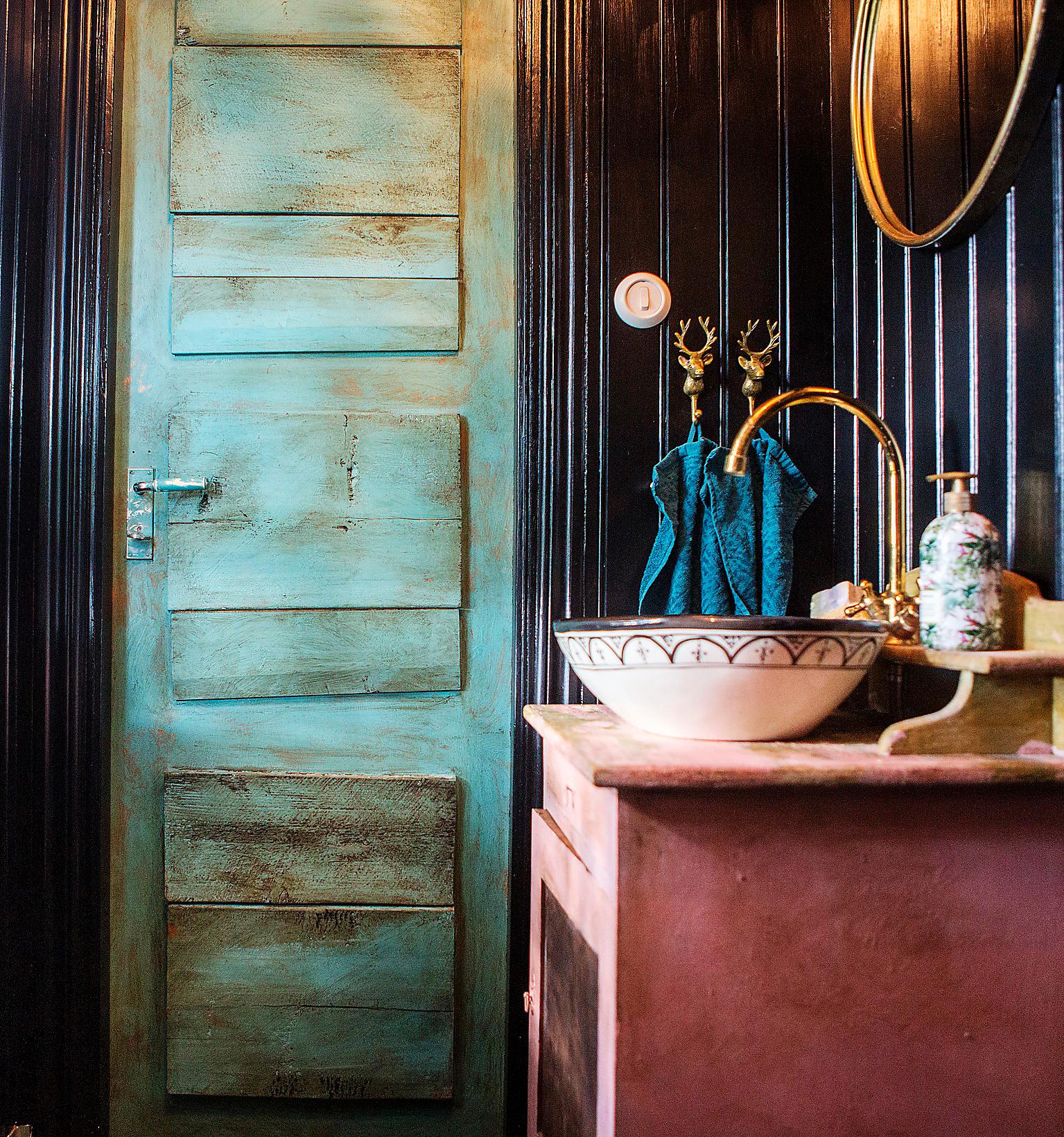 Toaletten på bottenvåningen har svart panel, en grön dörr och en rosa gammal kommod som paret har snickrat och målat. Handfat från Sidsid och blandare från Camargue. 
