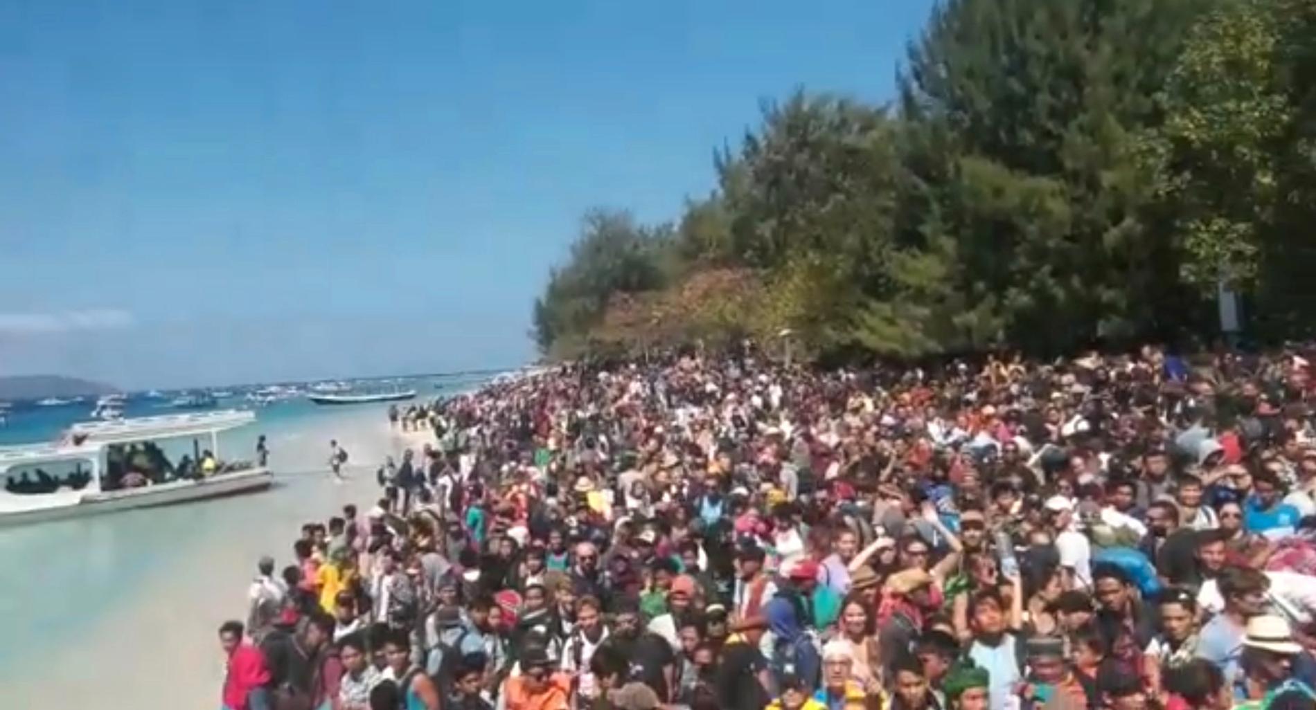 Folkmassor på stranden väntar på att få lämna Gili-öarna efter helgens jordbävning. 