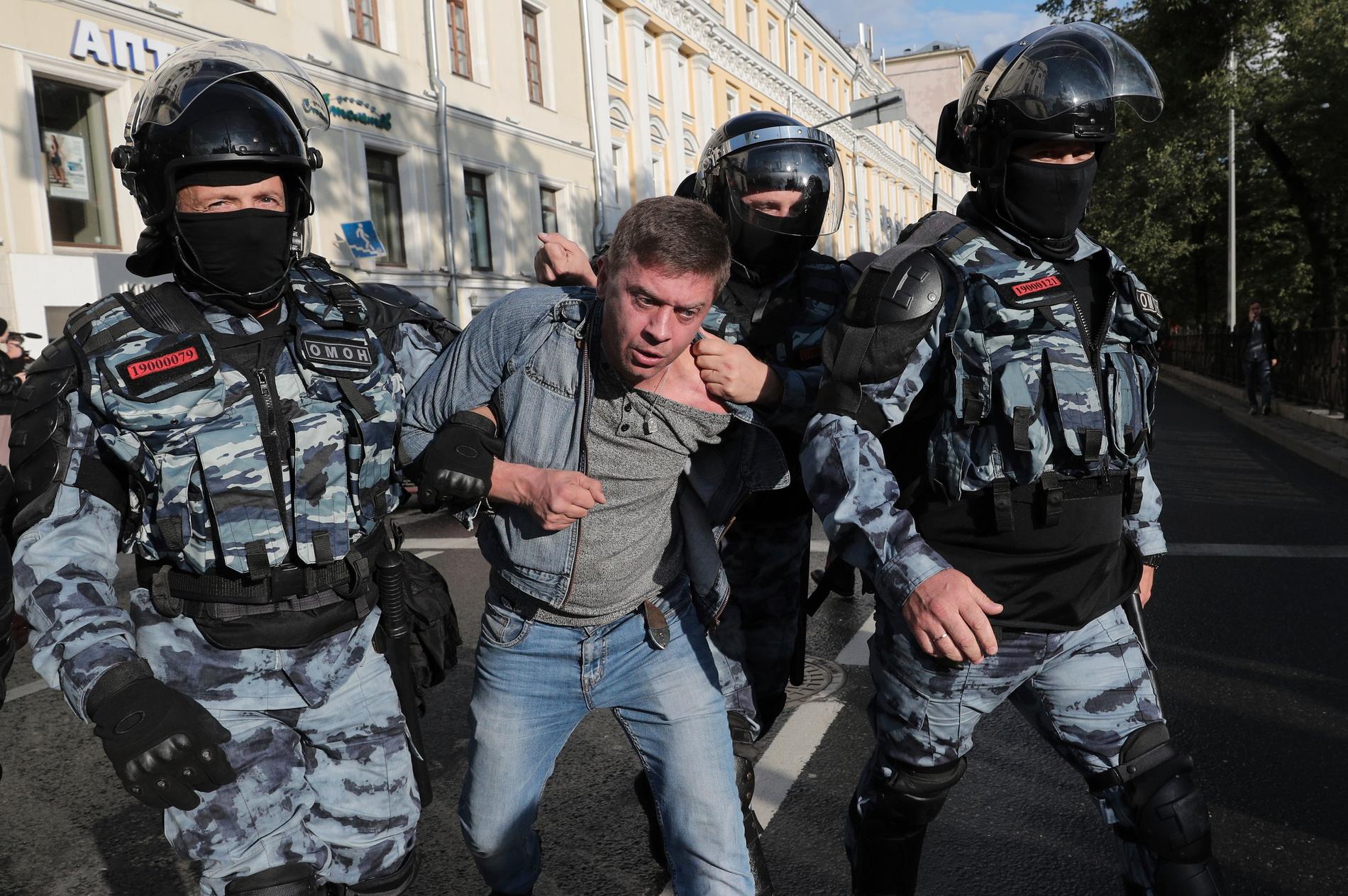 Poliser griper en demonstrant under lördagens regimkritiska protester i Moskva.