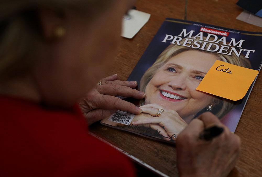 Hillary Clinton skriver autograf på tidningen.