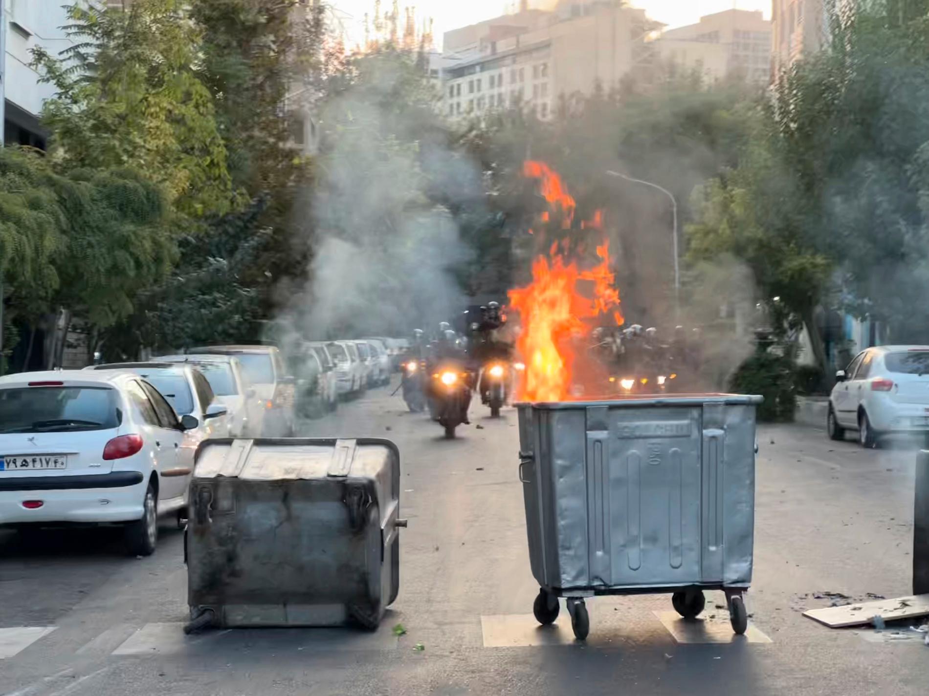 Demonstranter har satt eld på soptunnor för att stoppa kravallpolis i Teheran från protesternas inledning.