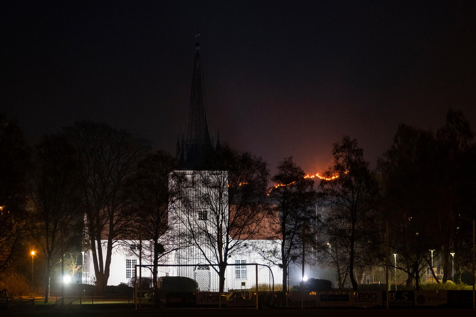 Det brinner i Sokndal kommun i Norge. På bilden Sokndals kyrka med lågorna i bakgrunden.